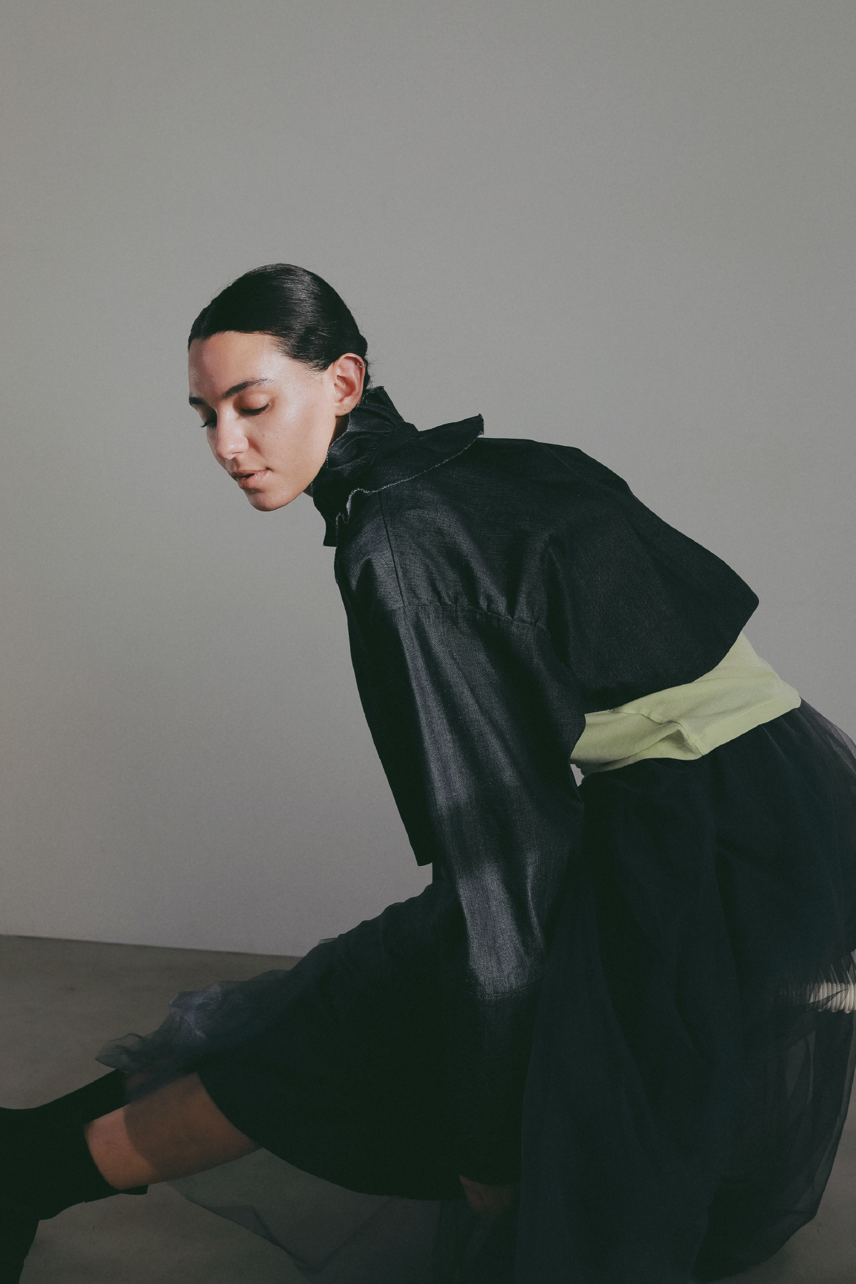 ブラックのジャケット・ライムグリーンのトップス・ブラックのスカートを着用した女性の画像