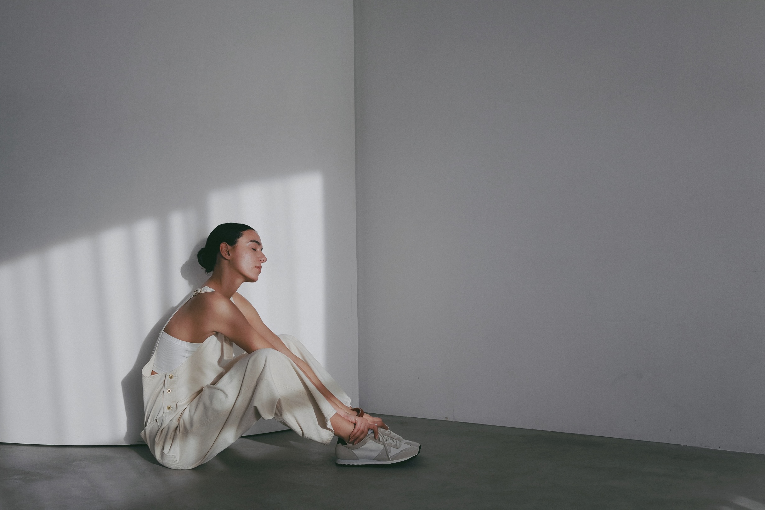 ホワイトのジャケット・ホワイトのオールインワンを着用した女性の画像