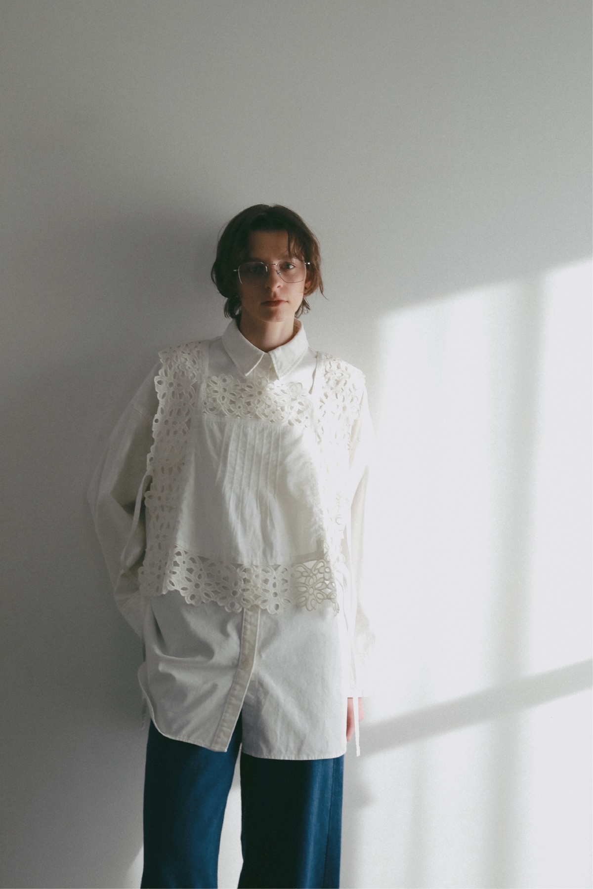 ホワイトのシャツ・ホワイトのビスチェ・デニムパンツを着用した女性の画像