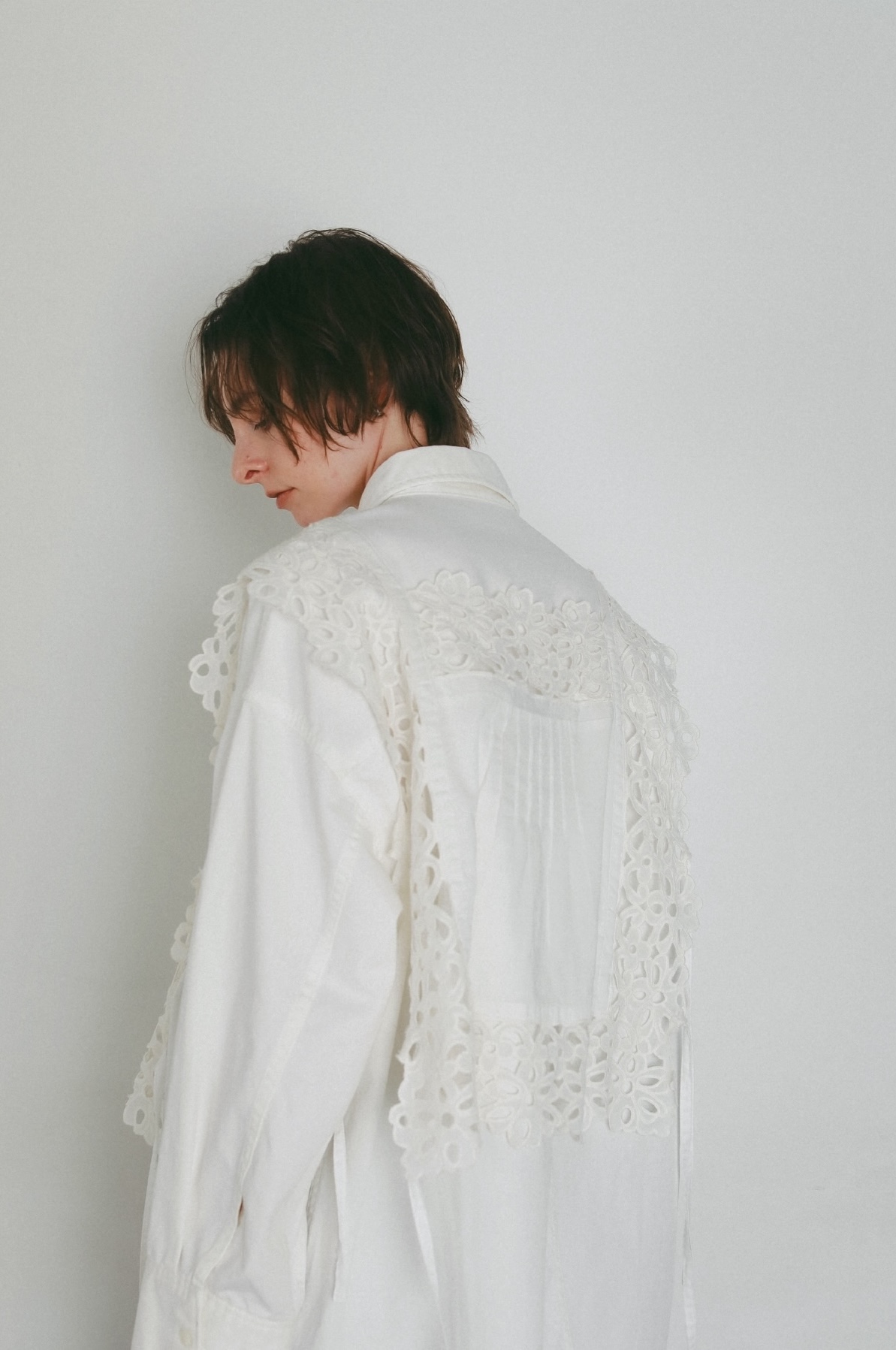 ホワイトのシャツ・ホワイトのビスチェを着用した女性の後ろ姿の画像