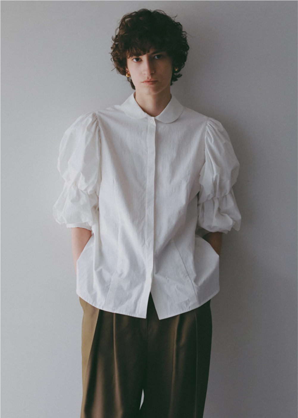 ホワイトのブラウス・カーキのパンツを着用した女性の画像