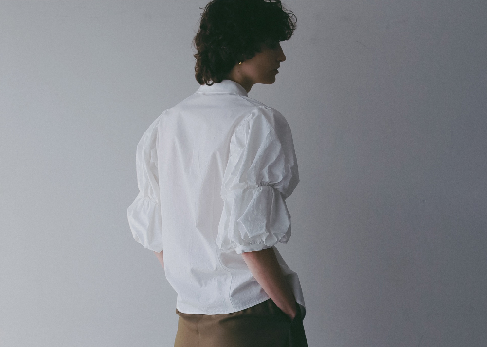 ホワイトのブラウス・カーキのパンツを着用した女性の後ろ姿の画像