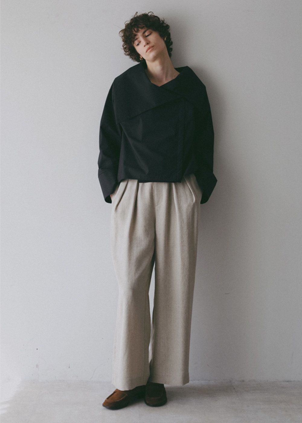 ブラックのブラウス・アイボリーのパンツを着用した女性の画像