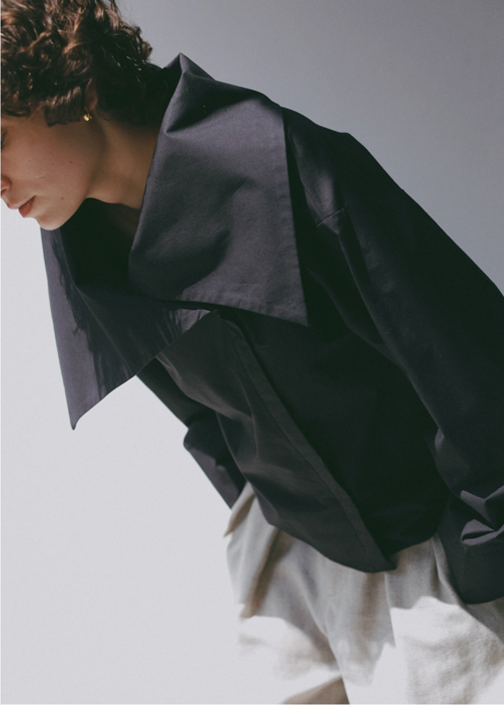 ブラックのブラウス・アイボリーのパンツを着用した女性の画像