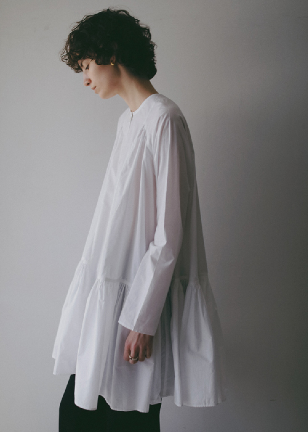 ホワイトのブラウス・ブラックのパンツを着用した女性の画像