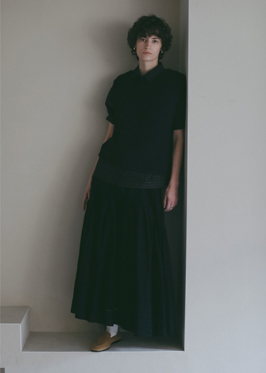 ブラックのチェック柄のブラウス・ブラックのスカートを着用した女性の画像