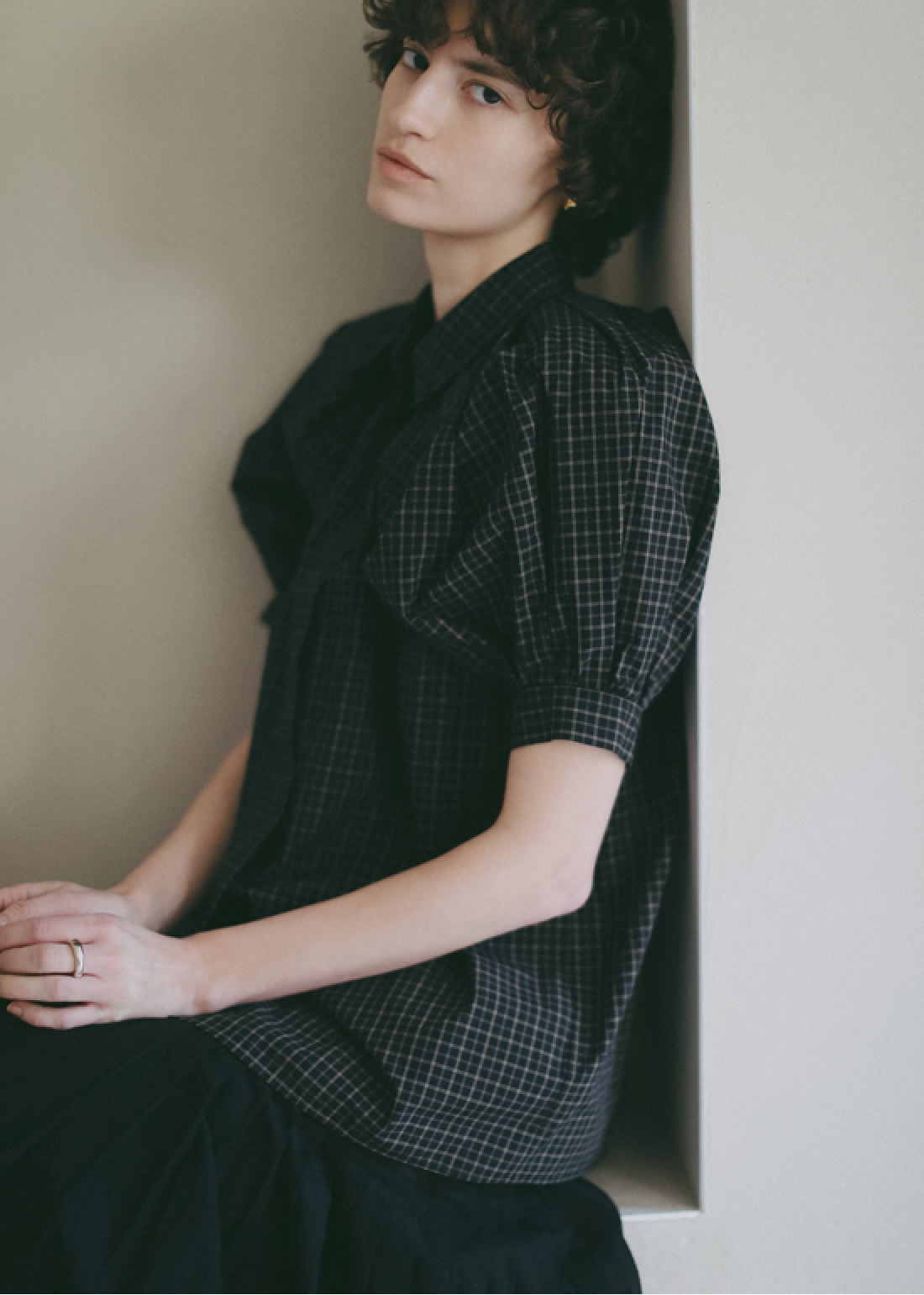 ブラックのチェック柄のブラウス・ブラックのスカートを着用した女性の画像